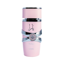 This image depicts a cylindrical, pale pink perfume bottle with the name "YARA" from the brand Lattafa. The bottle has a unique stacked design with silver bands wrapping around it, giving the appearance of three separate sections. The upper and lower sections are matte pink, while the middle section is glossy black, providing a striking contrast. A silver emblem with intricate detailing is centered on the middle band. The Arabic script, likely the name "YARA," is printed in black on the upper pink section.