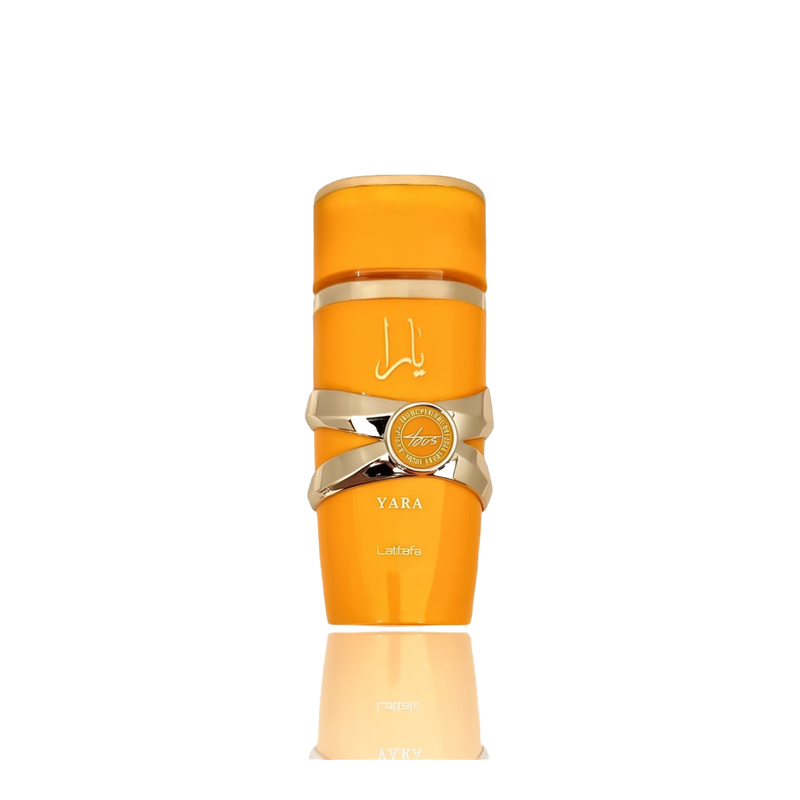 This image features a bright orange cylindrical perfume bottle with the name "YARA" from the brand Lattafa. The design is distinguished by a gold ribbon-like band wrapped around the center, with a circular emblem featuring text that may denote "EAU DE PARFUM NATURAL SPRAY". The Arabic script for "YARA" is placed above the gold band. The bottle has a glossy finish and is presented against a gradient background that fades from white at the top to a light reflection of the bottle at the base.