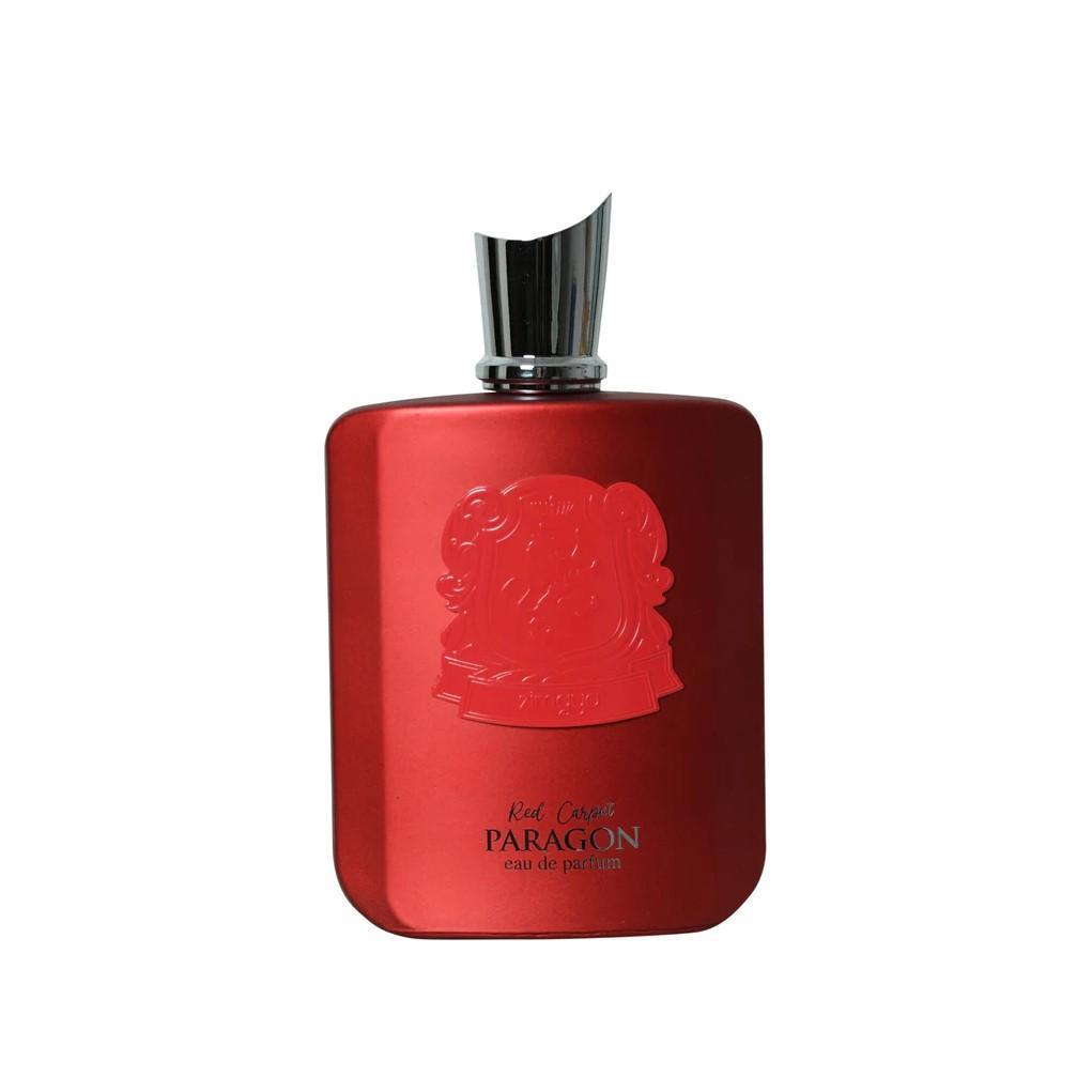 The image shows a bottle of "Red Carpet Paragon" eau de parfum by Zimaya. The perfume bottle is sleek and rectangular with a striking, matte red finish. It features an ornate embossed crest near the top. Below the crest, the text reads "Red Carpet PARAGON" and "eau de parfum" in black. The bottle has a modern, angular silver cap that complements its sophisticated design.