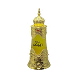 The image features a luxurious perfume bottle with a traditional and opulent design. The bottle has a clear glass body with a golden-yellow liquid visible inside, suggesting a rich and warm scent. It is adorned with elaborate golden decorations, including intricate arabesque patterns, and a red gemstone in the center adds a touch of elegance. The cap is a golden dome with a pointed tip, reminiscent of Middle Eastern architecture. 
