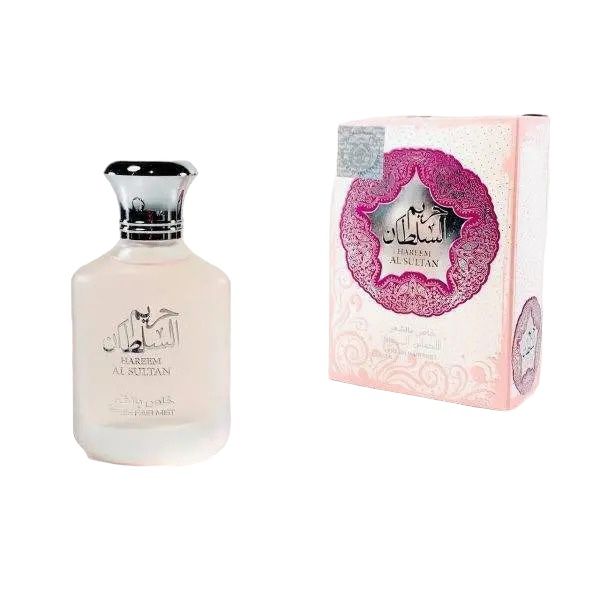 The image shows a fragrance product consisting of a bottle and its packaging box. The bottle is translucent with a frosted glass appearance and has a black cap. It features elegant black script and design on the front. The packaging box is predominantly white with intricate pink and silver designs surrounding a central emblem, giving it a luxurious and ornate appearance. The central emblem on the box is stylistically similar to the design on the bottle, suggesting that they are part of a matching set.